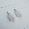 Iridescent puzzle piece resin earrings on white wood background